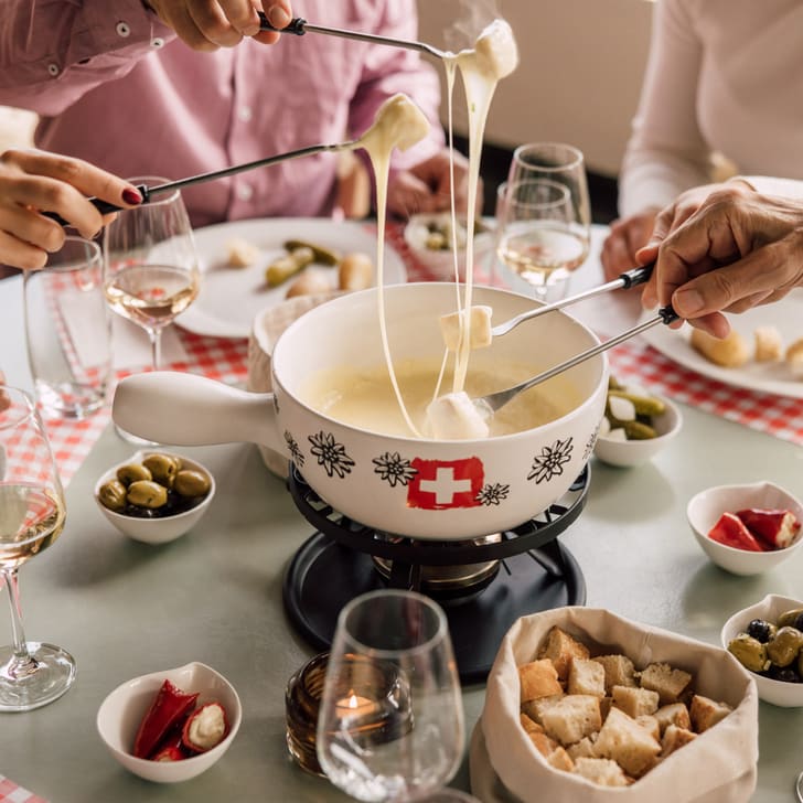 Fondueessen mit Freunden, Brotwürfel und Oliven auf Tisch.