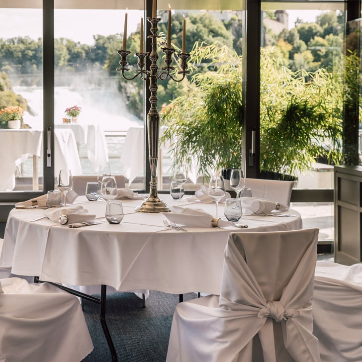 Elegantes Esszimmer mit Blick auf Wasserfall und Bäume.