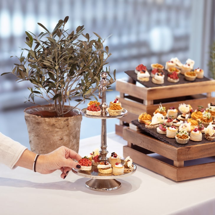 Person nimmt einen Snack von einem Tisch mit kleinen Desserts.