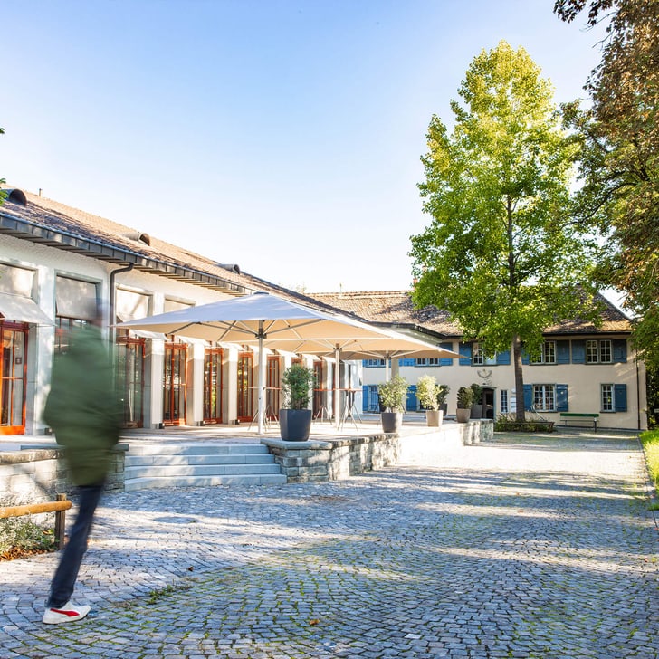 Person walking past a sunny building with a terrace.
