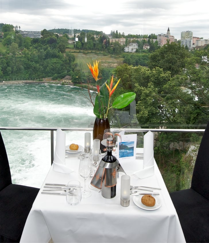 Tisch für zwei mit Fluss- und Landschaftsausblick hinter Glaswand.