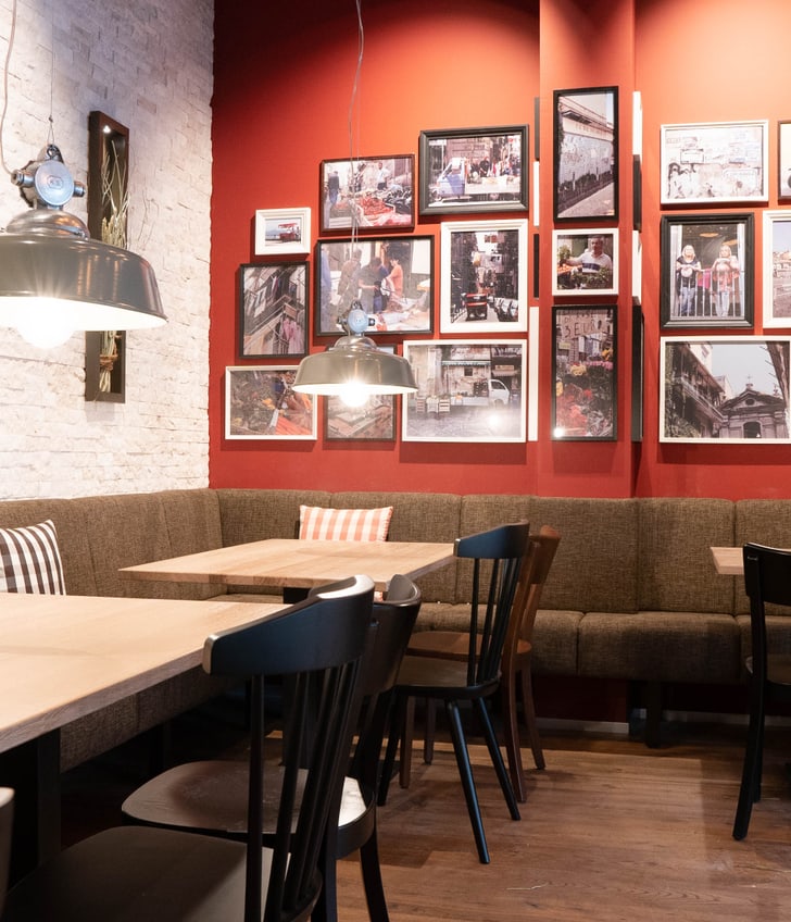 Gemütliches Café mit Holztischen und Bilderwand.