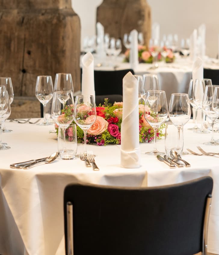 Elegant gedeckter runder Tisch mit Blumenarrangement.