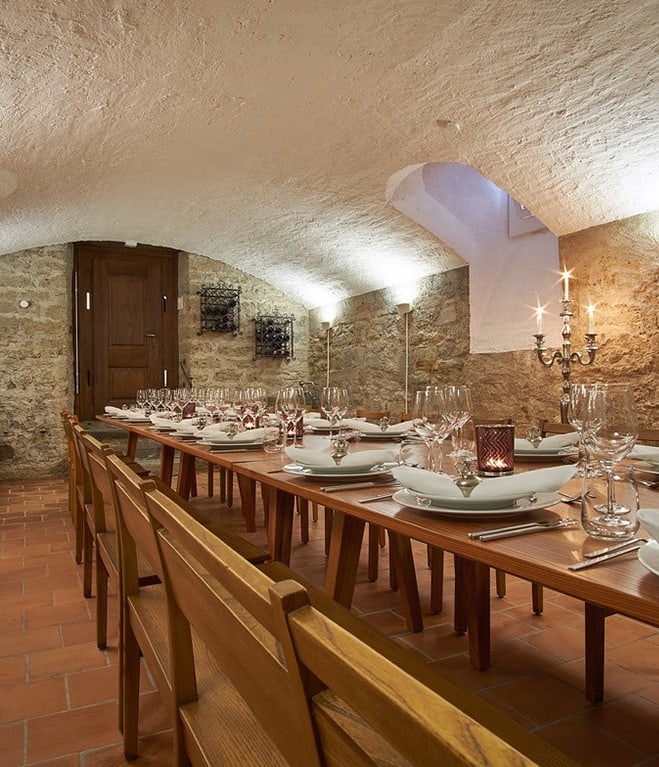 Langer Tisch in einem Gewölbekeller mit Kerzenleuchtern.