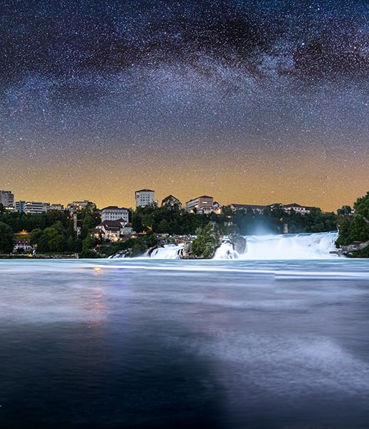 Nachthimmel über Rheinfall mit Gebäuden am Ufer.