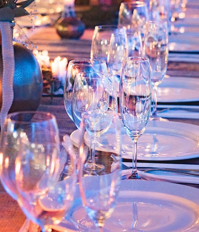 Eleganter Tisch mit Gläsern und Tellern dekoriert für Abendessen.