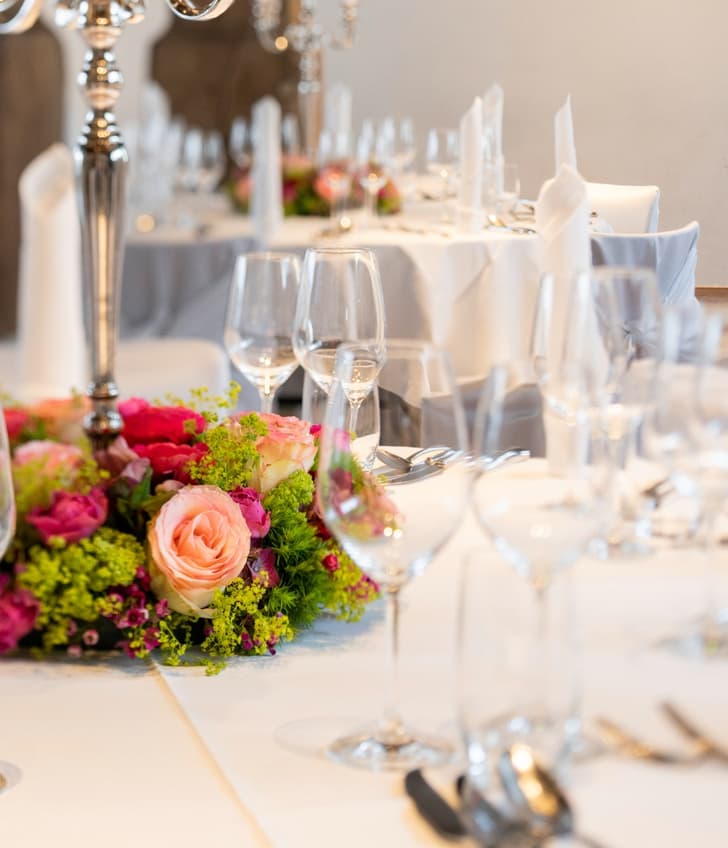 Elegant gedeckter Tisch mit Blumen, Gläsern und Kerzenständer.