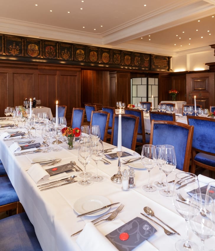 Elegantes Restaurant mit langen, eingedeckten Tischen und blauen Stühlen.