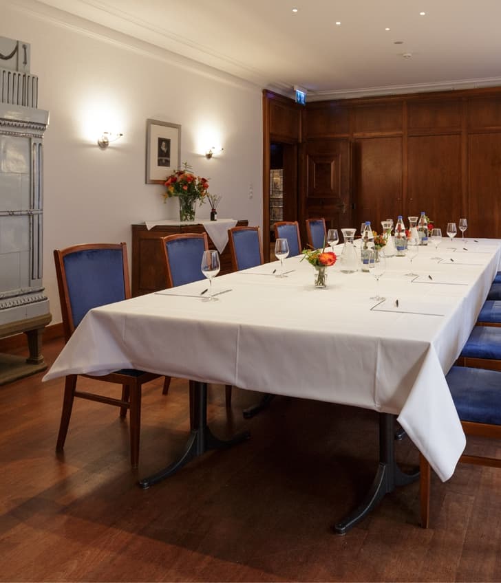 Eleganter Esszimmer mit eingedecktem Tisch und Kachelofen.