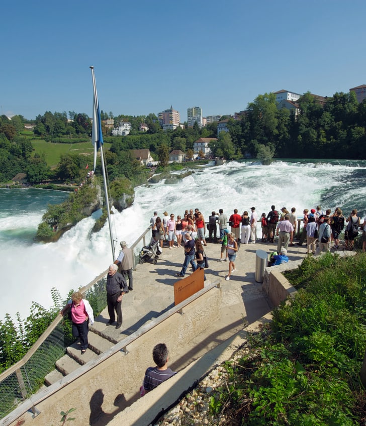 Menschenmenge betrachtet Rheinfall bei Sonnenschein.