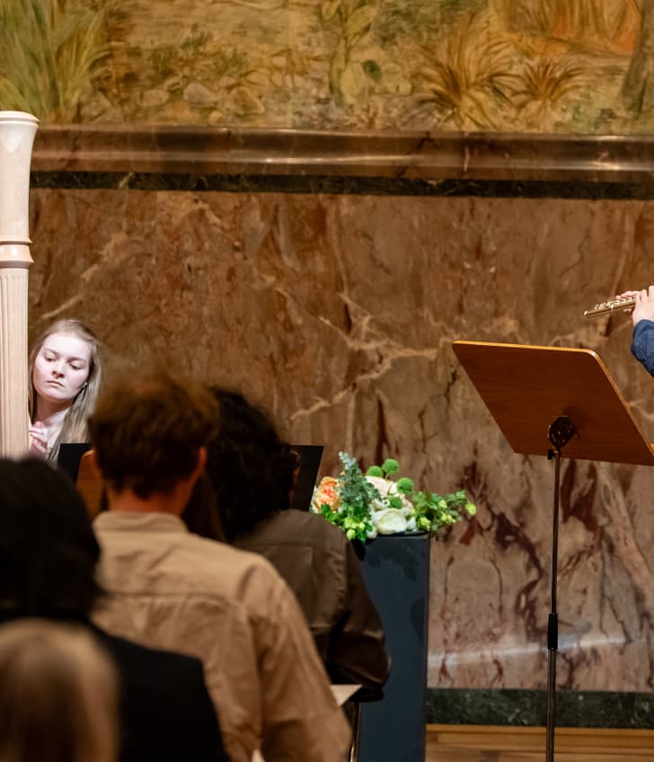 Harfenspielerin und Flötist bei Konzertauftritt vor Publikum.