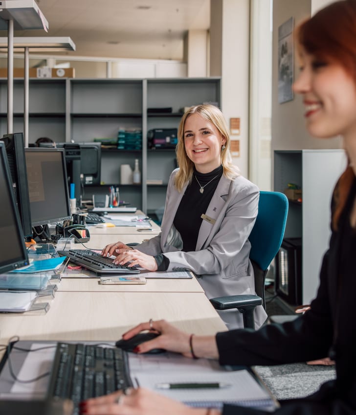 Zwei Frauen arbeiten an Computern im Büro.