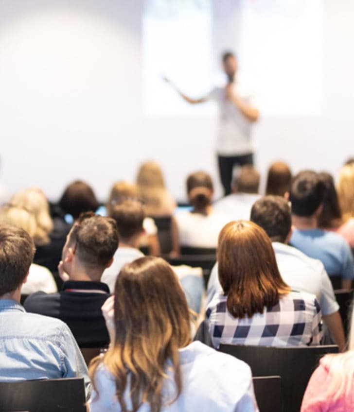 Person hält Präsentation vor Publikum in einem Raum.