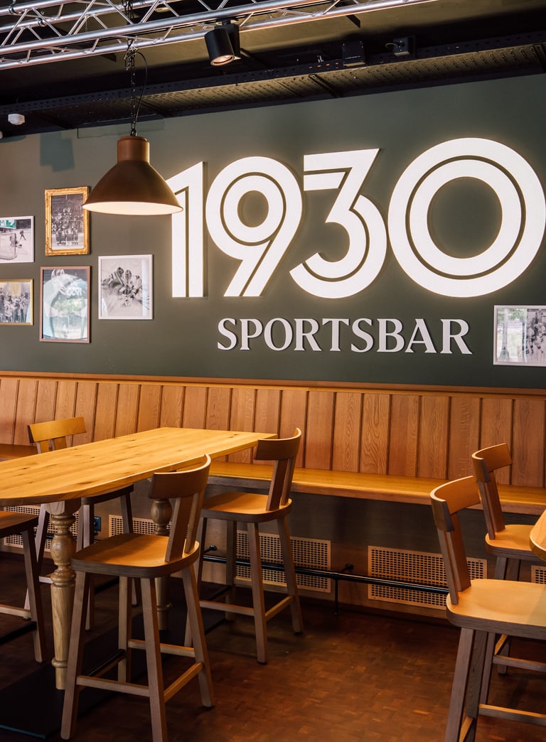 Innenraum der 1930 Sportsbar mit Holztischen und dekorierten Wänden.