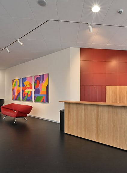 Moderne Lobby mit rotem Sofa, Holztheke und bunter Kunst an der Wand.