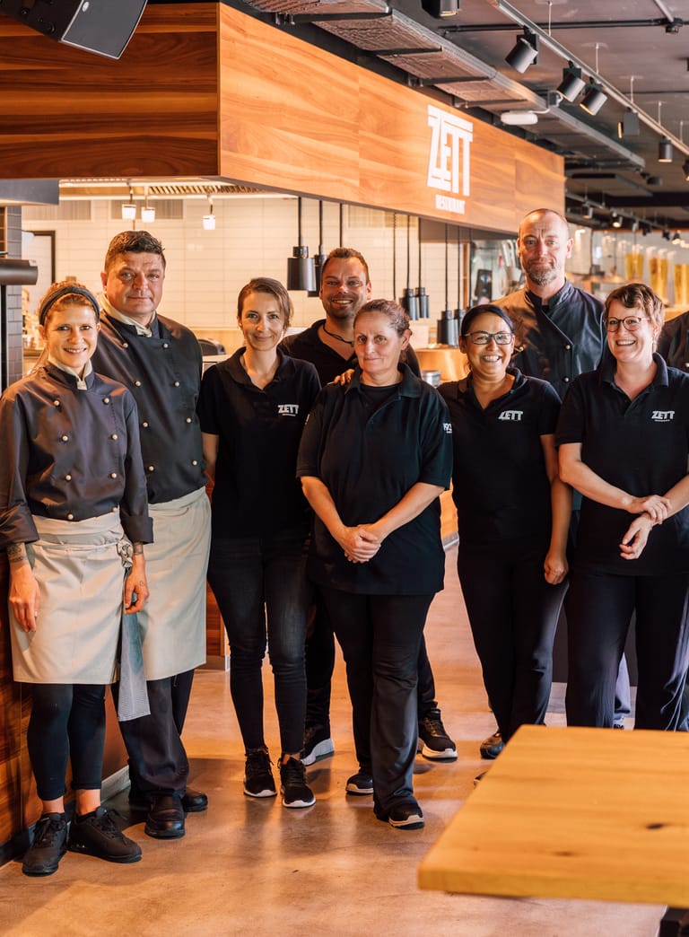 Gruppe von Restaurantmitarbeitern in Uniform im Innenbereich des Restaurants.