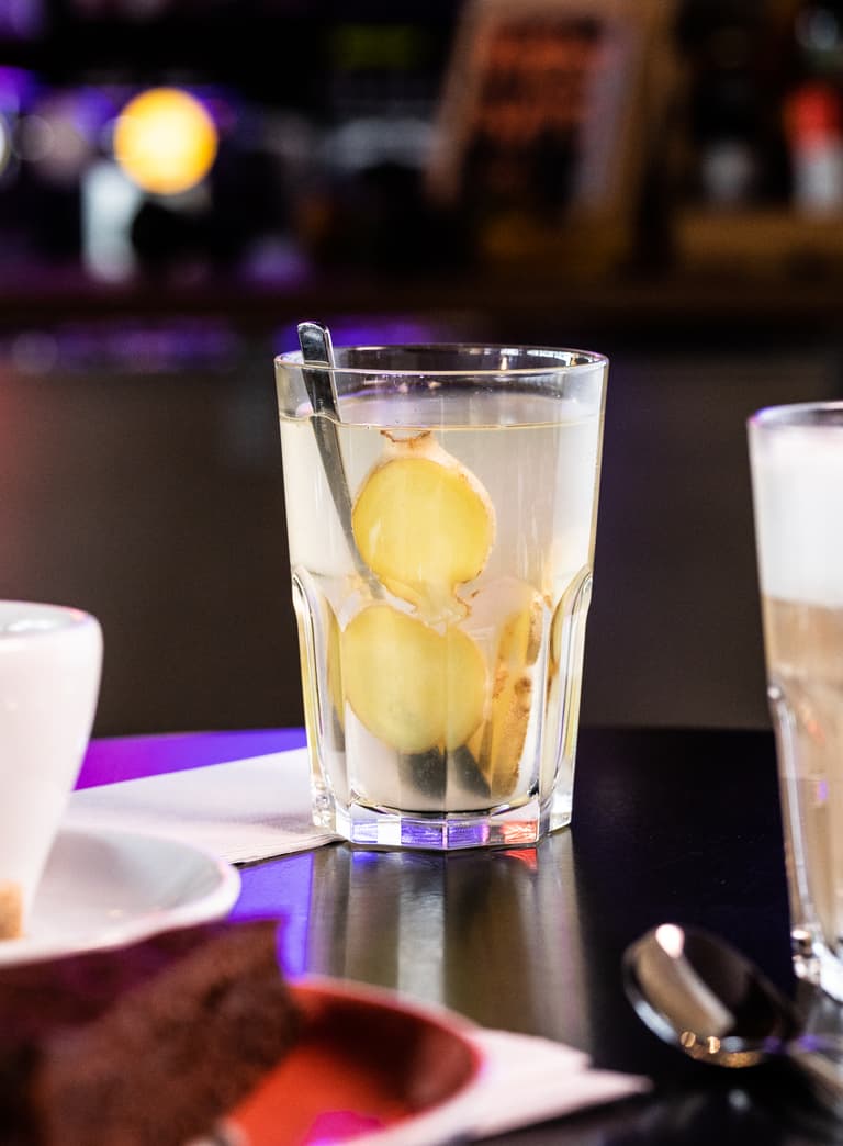 Glas mit Ingwertee und Latte auf Tisch in Café.