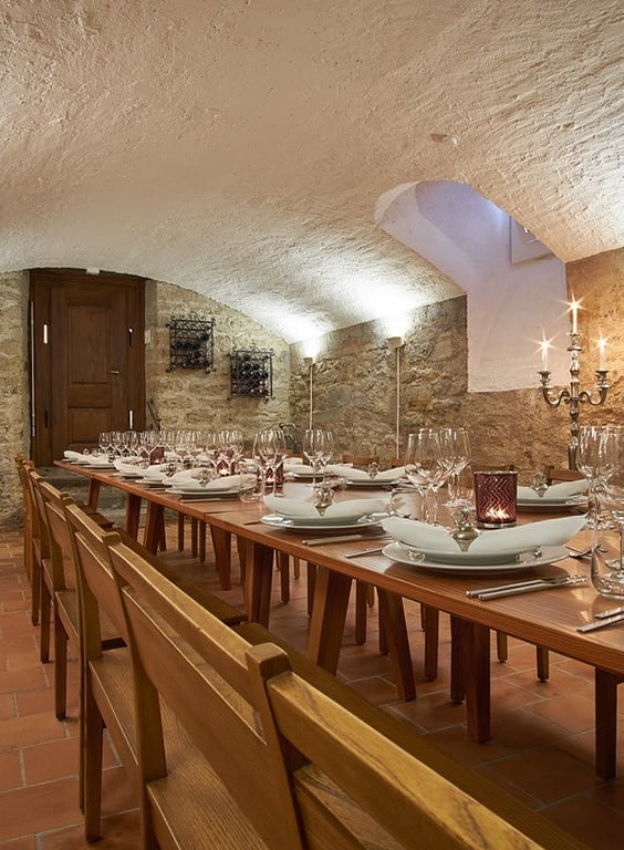 Langer Tisch in einem Gewölbekeller mit Kerzenleuchtern.