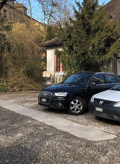 Zwei geparkte Autos vor Gebäude im Freien.