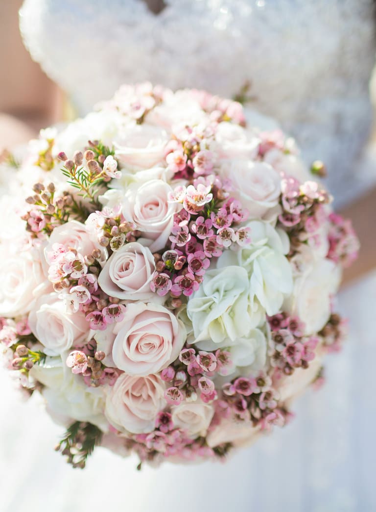 Braut hält Blumenstrauss, Schafe im Hintergrund.