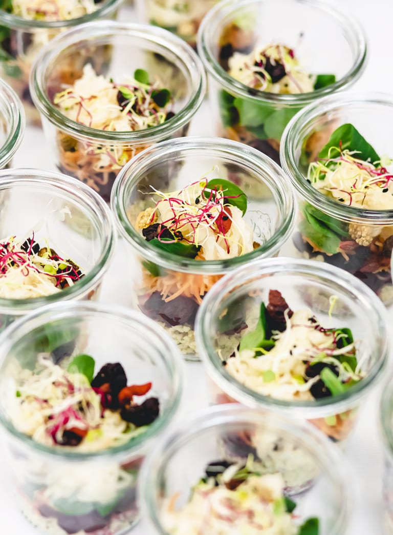 Mehrere Gläser mit Salat und Sprossen gefüllt.