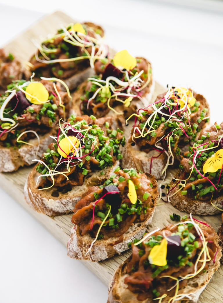 Mehrere belegte Baguettescheiben mit Gemüse und Kräutern.