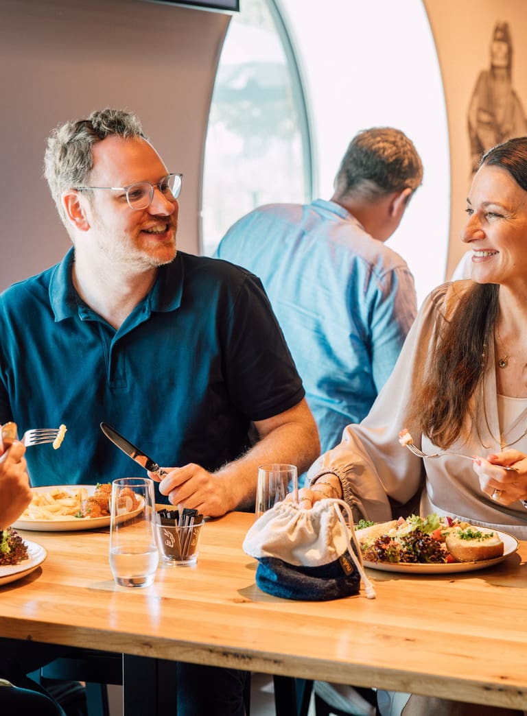 Gruppe von Menschen isst und unterhält sich an einem Tisch.