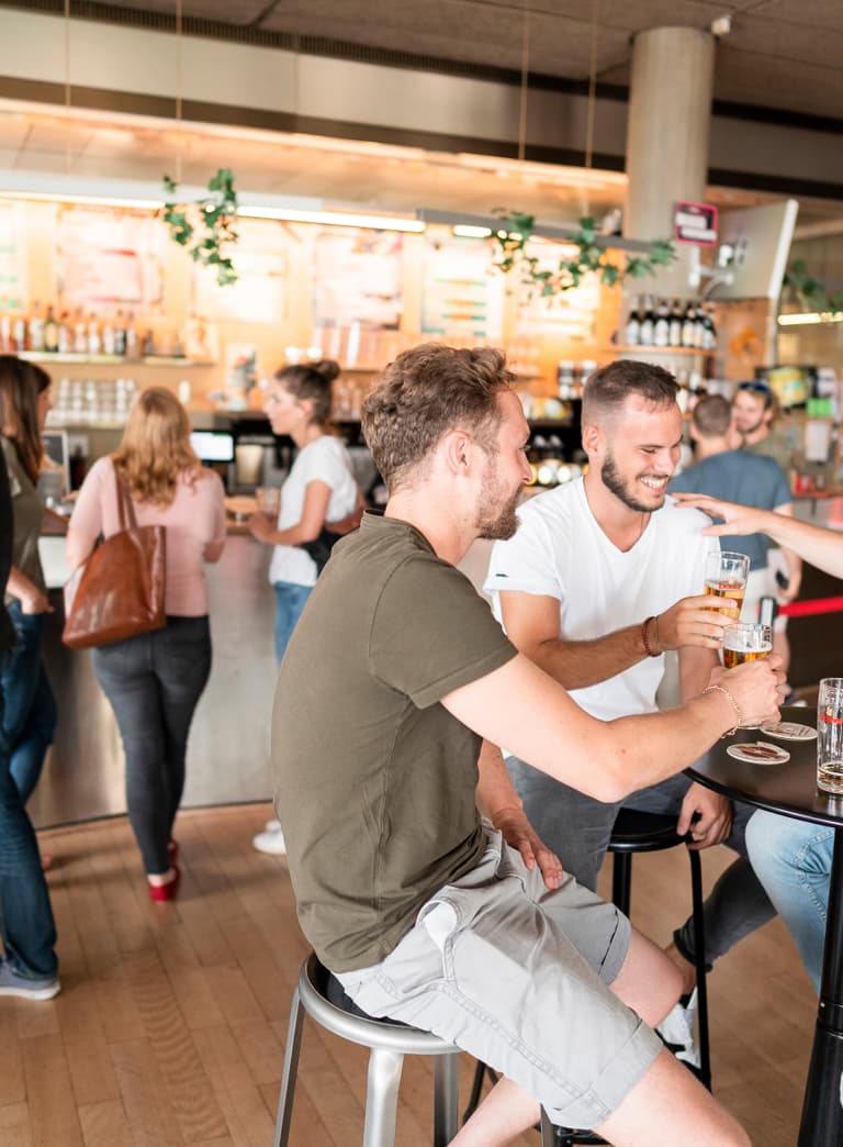 Menschen geniessen Getränke in einer belebten Bar.