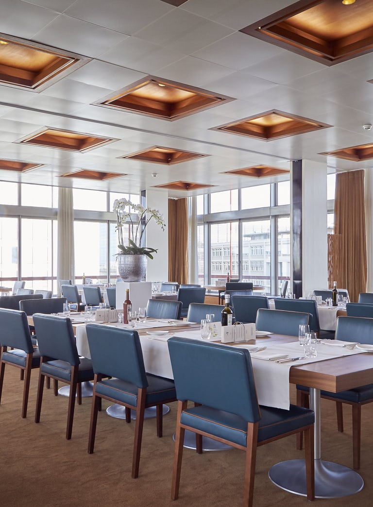 Modernes Restaurant mit gedeckten Tischen und Panoramafenstern.