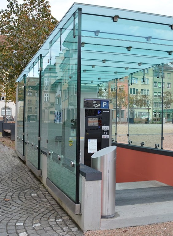 Glasüberdachung mit Parkscheinautomat in städtischem Platz.
