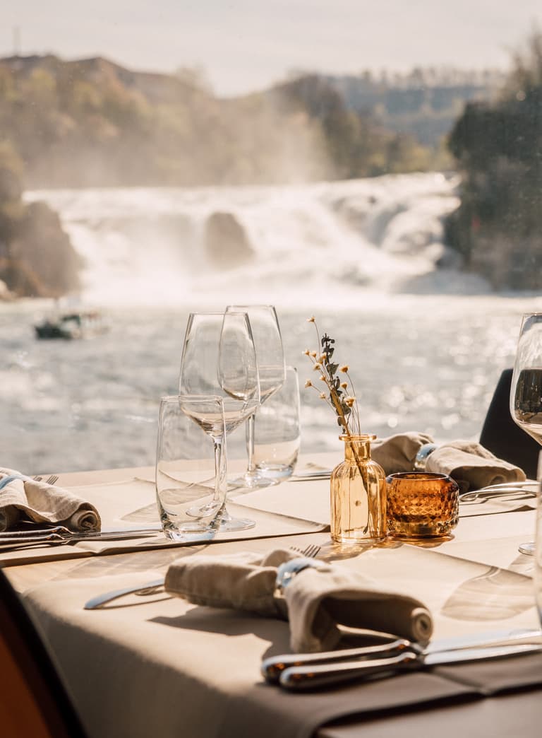 Gedeckter Tisch mit Wasserfall im Hintergrund.