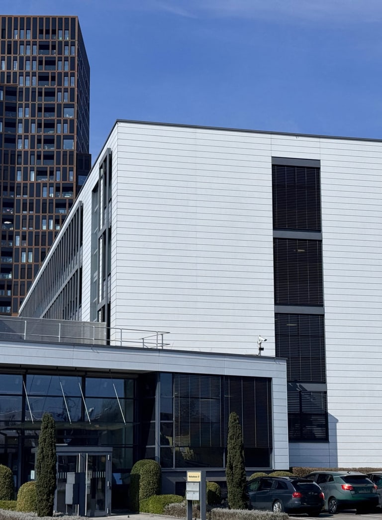 Modernes Gebäude mit Firmenlogo bei sonnigem Himmel.