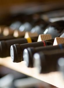 Weinflaschen auf einem Holzregal liegend.