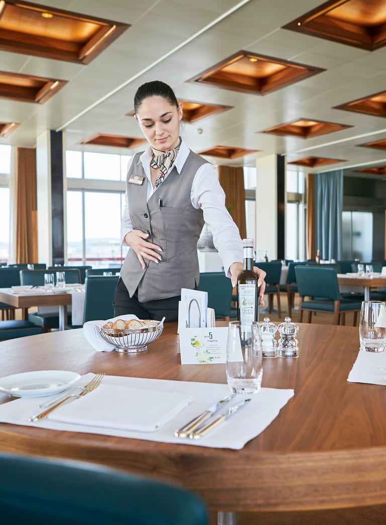 Kellnerin deckt Tisch in elegantem Restaurant ein.