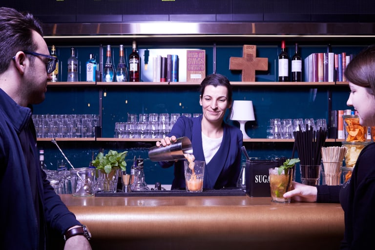 Barkeeper mixt Getränke für zwei Gäste am Tresen.