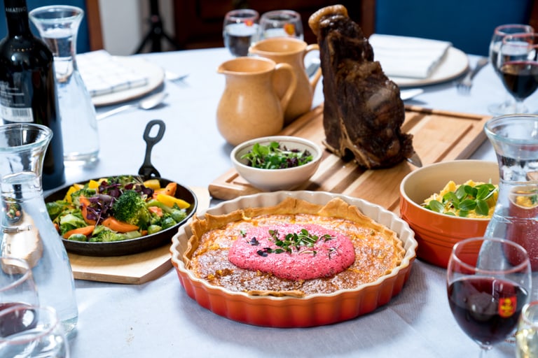 Festliches Essen mit Quiche, Fleisch, Salat auf Tischgedeck.