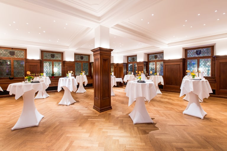 Eleganter Veranstaltungsraum mit Stehtischen und Holzvertäfelung.