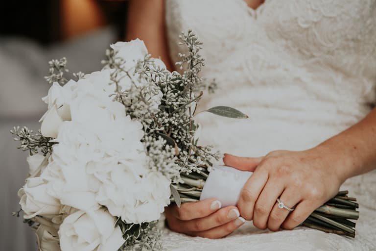 Braut mit Blumenstrauss in der Hand, Nahaufnahme des Kleides und Rings.