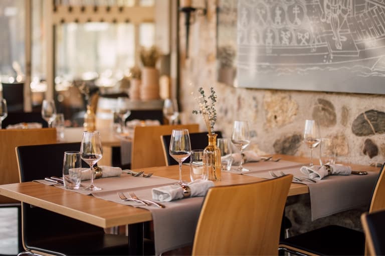 Elegantes Restaurant mit gedeckten Tischen und Steinwänden.