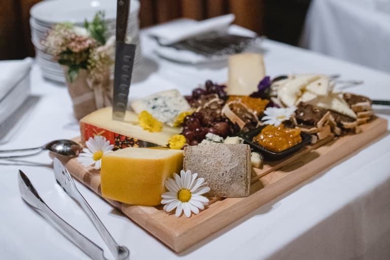 Käseplatte mit verschiedenen Käsesorten und Blumen auf Tisch im Restaurant.