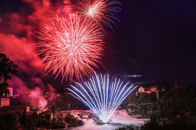 Feuerwerk über dem Rheinfall bei Nacht.