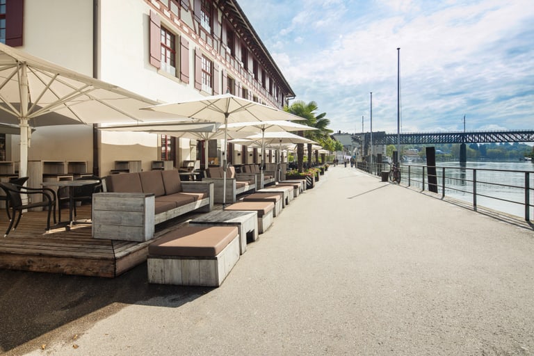 Aussenterrasse mit Sitzbereich und Sonnenschirmen am Flussufer.