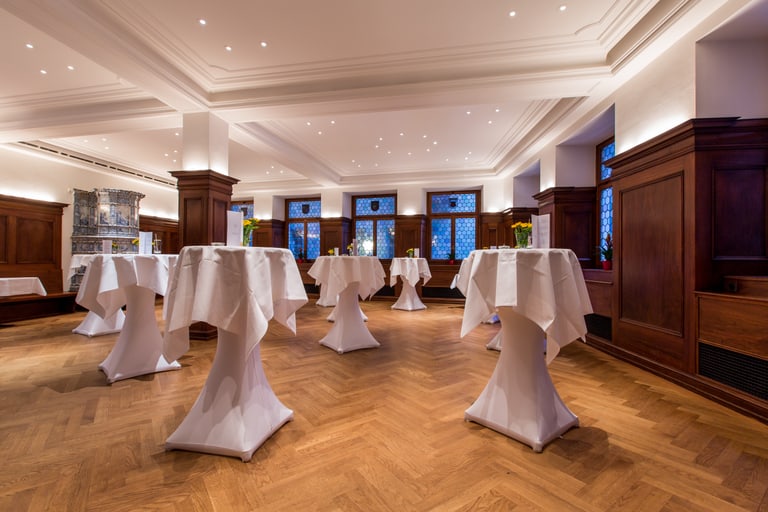Eleganter Raum mit Stehtischen und Holzverkleidung.
