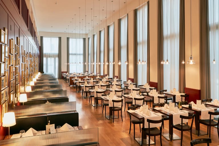 Elegantes Restaurant mit langen Tischreihen und Wandkunst.