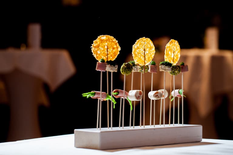 Gourmet-Appetizer auf Holzspiessen arrangiert auf einem Tisch.