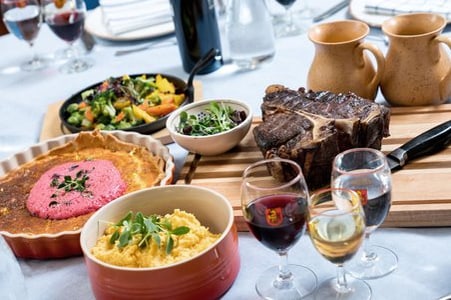 Tisch mit verschiedenen Speisen und Getränken, darunter Fleisch und Salate.