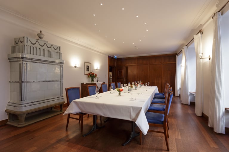 Eleganter Speiseraum mit Tisch, blauen Stühlen und Kachelofen.
