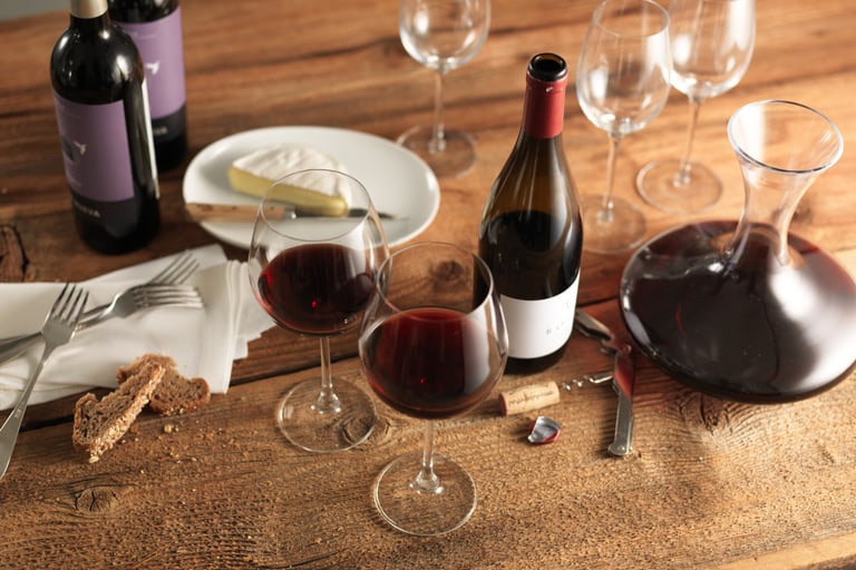 Wein und Käse auf einem Holztisch mit Gläsern und Dekanter.
