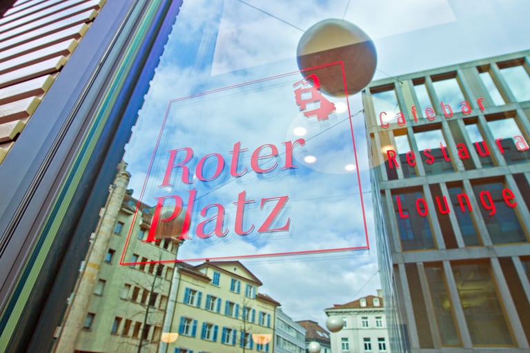 Fensterspiegelung mit rotem Text 'Roter Platz'.
