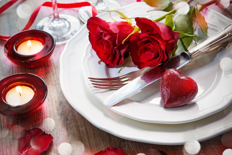 Romantisches Abendessen-Setup mit Rosen und Kerzen.